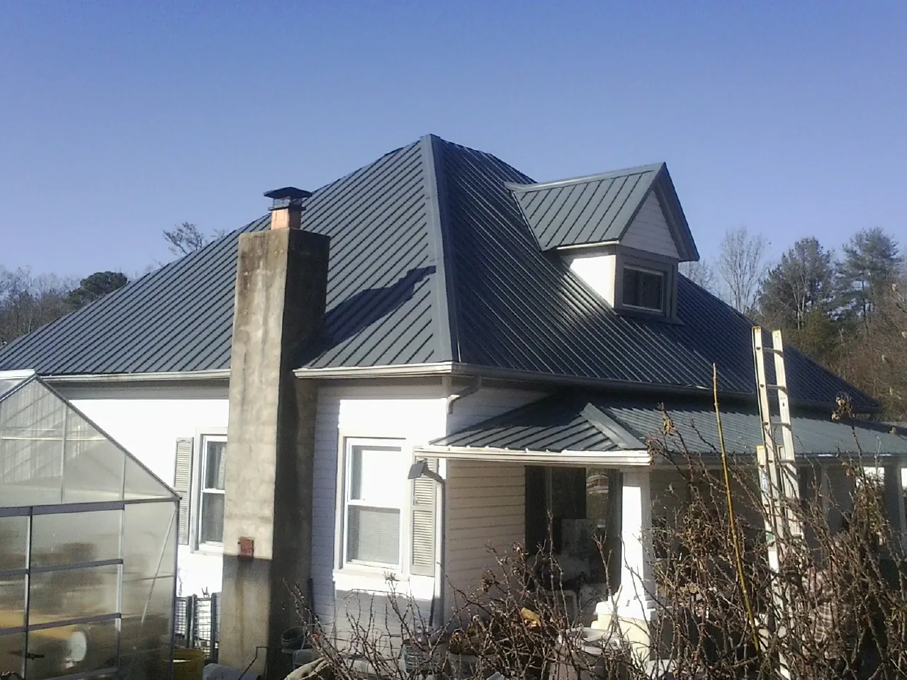Dark blue standing seam metal roof on a white farmhouse with dormer — Slate & Tile Roof Repair by Roofing Brothers in West Roxbury