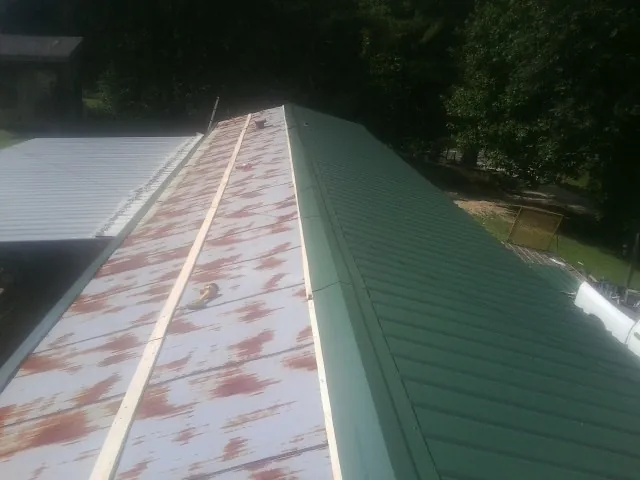 Old rusted panels beside newly installed green metal roofing — Wind Damage Roof Repair by Roofing Brothers in West Roxbury