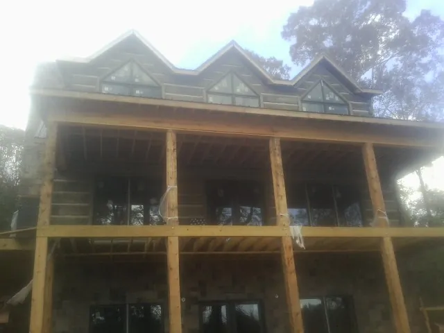 Dormers and porch framing on a large log home under construction — Roof Coating work by our crew in West Roxbury