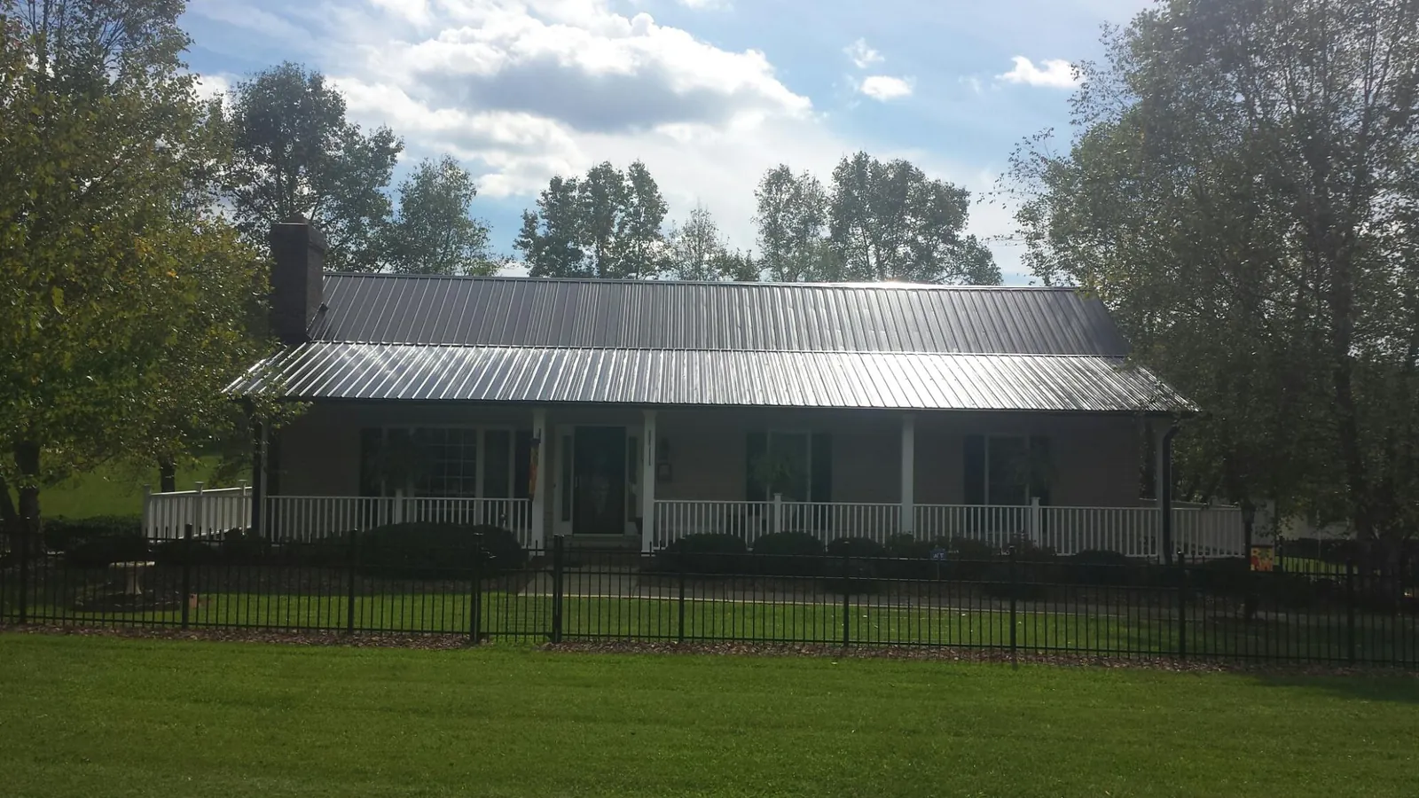 Gray metal roof on a brick ranch with a full width front porch — Gutter Guard Installation work by our crew in West Roxbury