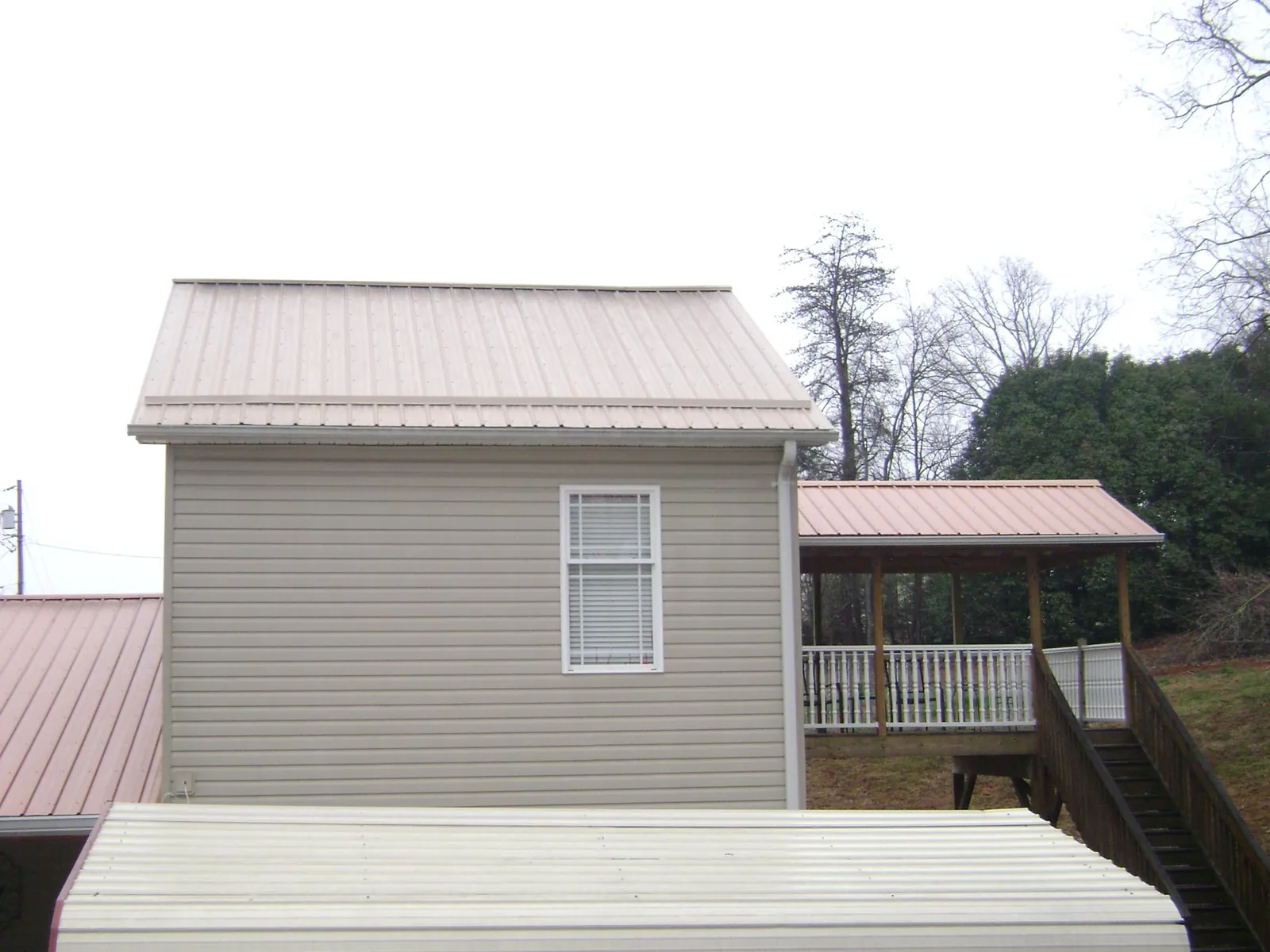 Tan metal roofs on a two story addition and attached porch, from a Roof Replacement job in West Roxbury