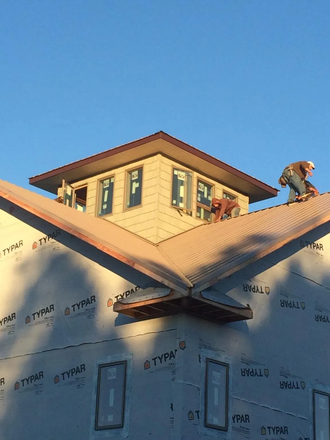 Roofers working around a rooftop cupola on a new metal roof at sunset — Roof Waterproofing in West Roxbury by Roofing Brothers